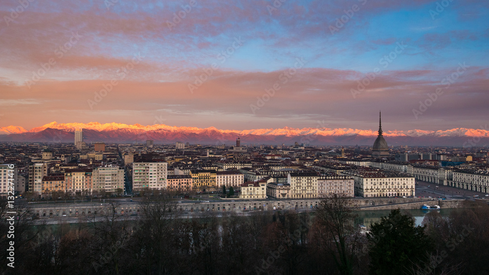 Torino (Turin, Italy): expansive cityscape at dusk with scenic colorful light on the snowcapped Alps in the background.