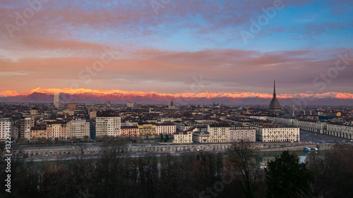 Torino (Turin, Italy): expansive cityscape at dusk with scenic colorful light on the snowcapped Alps in the background.