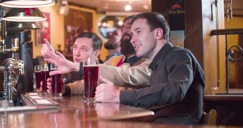 Friends group talks and drinks beer at pub bar 4k close-up video. Men having fun, looking and discussing something, drinks brown lager or ale from glasses Friends group talks and drinks beer at pub bar 4k close-up video. Men having fun, looking and discussing something, drinks brown lager or ale from glasses