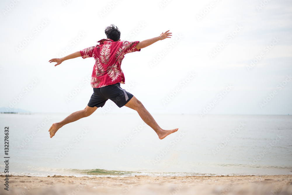 Athletic young man enjoying the summer, jumping in a tropical beach.