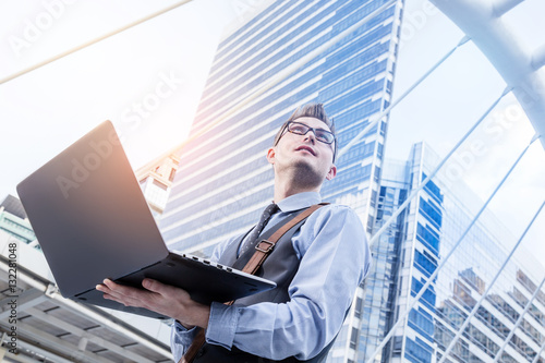 Wallpaper Mural Young handsome businessman standing with laptop in the big city Torontodigital.ca