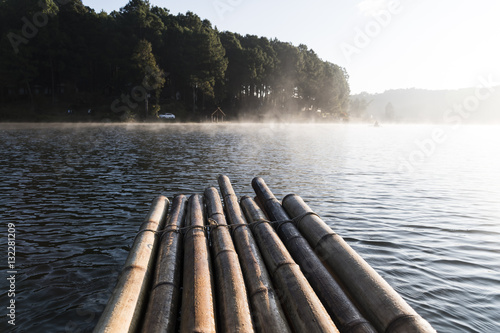 The bamboo raft floating on the reservoir with mist in the morni