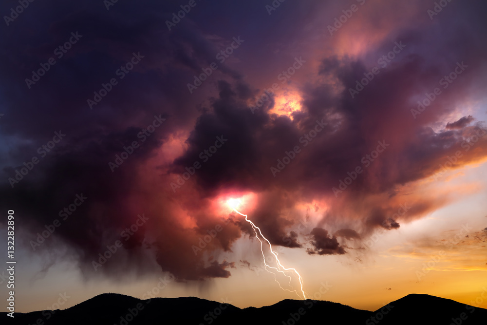 Lighting bolt striking from colorful clouds at sunset in the Nevada desert