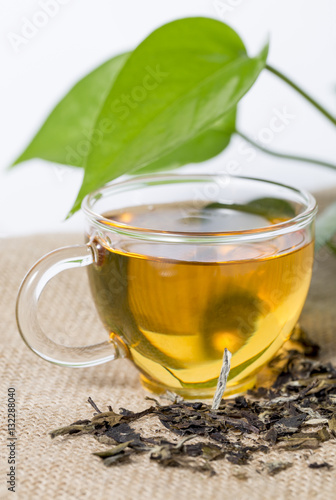Cup with tea and green leaf on the white background