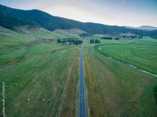 Aerial view of Omeo highway among green fields and hay bales in Mitta Mitta Valley, Victoria, Australia