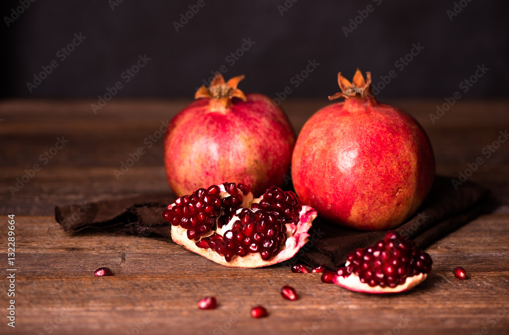 Pomegranate fruits with grains on wooden table. Dark moody. Life style. Pomegranate fruits with grains on wooden table. Dark moody. Life style.