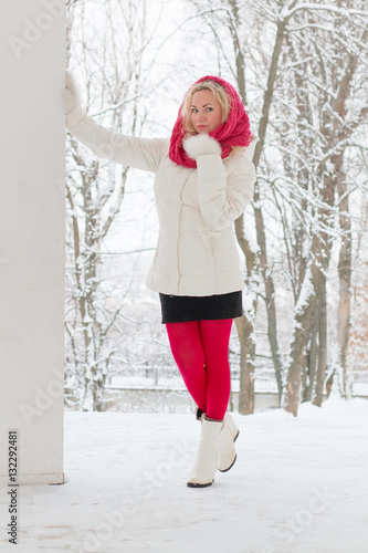 Winter portrait of beautiful woman in pink scarf and white coat. Blonde lady with green eyes.
