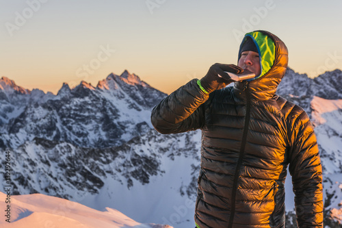 Hiker in winter drink a small sip from the hip flask in the mountains.