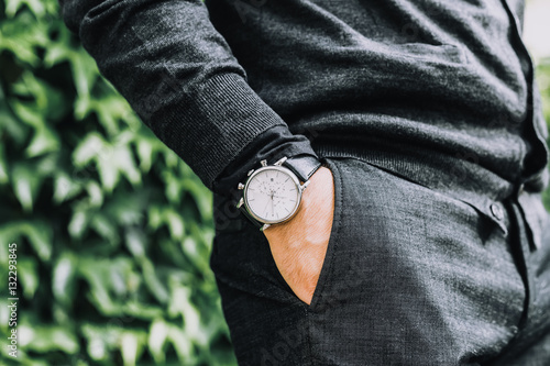closeup fashion image of luxury watch on wrist of man.body detail of a business man.Man's hand in a grey shirt with cufflinks in a pants pocket closeup. Tonal correction
 photo