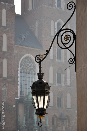 Antique metal street lamp on the background of St Mary's church in the fog. Krakow, Poland.