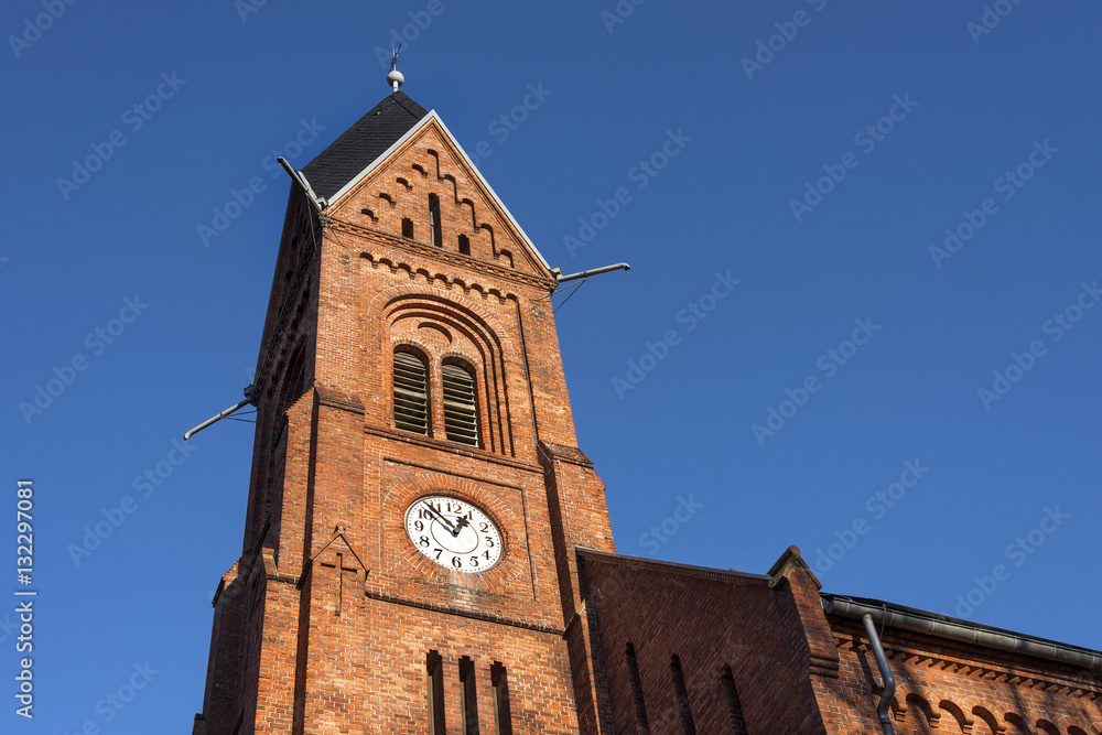Germany, Greifswald, Wieck: Steeple of local neo-Romanesque church (Bugenhagenkirche) with tower clock and blue sky.