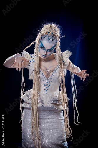 emotional actress woman in makeup and costume queen of elves or snow queen on blue-black background photo