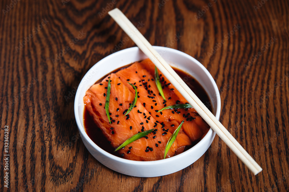 Japanese style salmon with sesame on a white plate, chopsticks Japanese style salmon with sesame on a white plate, chopsticks