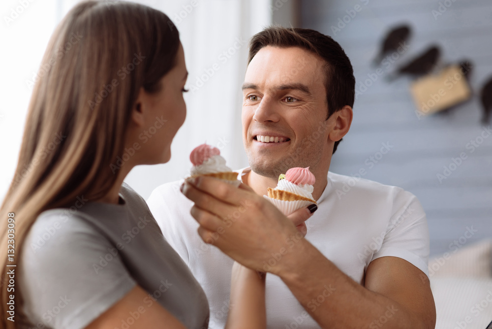 Cheerful positive man feeding his girlfriend Cheerful positive man feeding his girlfriend