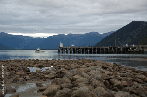 Boat departs a fishing pier at Jackson Bay New Zealand photo