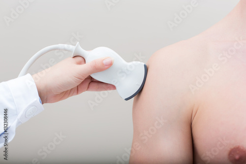 Female doctor visiting her male patient with ultrasound in medical center.