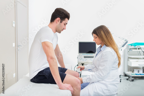 Female doctor visiting her male patient with ultrasound in medical center.