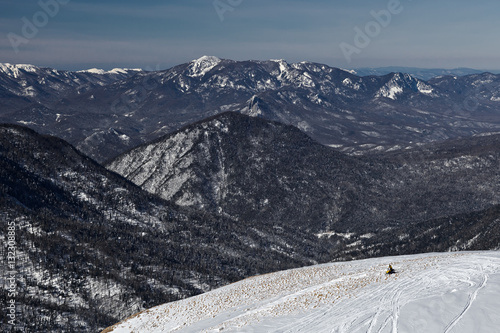 A lone rider on a snowmobile on a mountain top in the National Nature Reserve in Adygea, Russia.