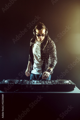 DJ mixing music on mixer on dark background