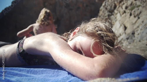 girl sunbathing on the beach on a towel and looking into the lens photo