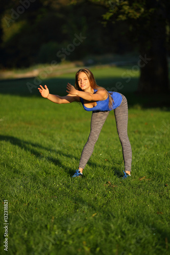 Young woman doing forward bend on grass