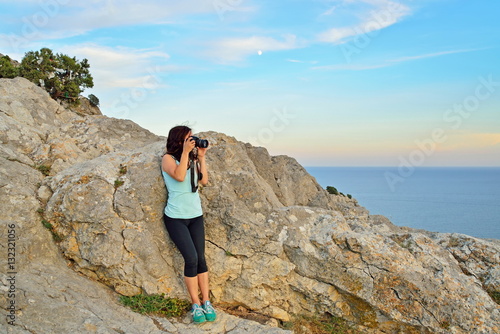 Girl tourist photographing the landscape at sunset