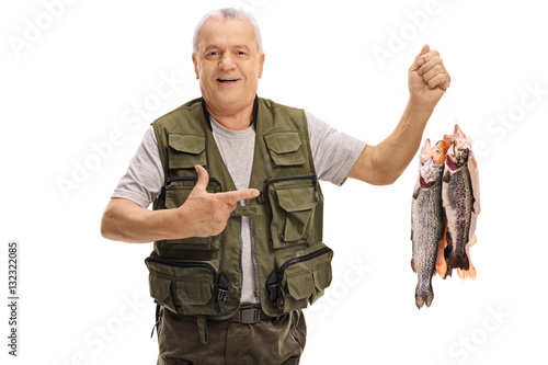 Joyful mature fisherman holding freshly caught fish and pointing
