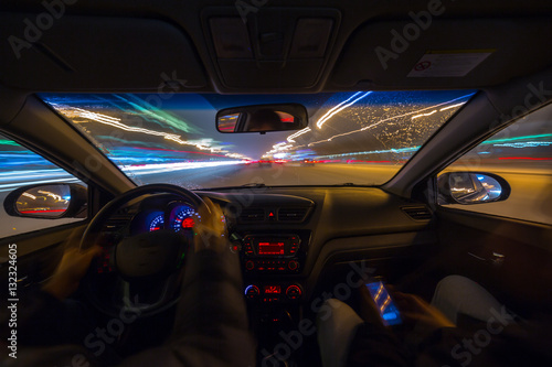 Night road view from inside car natural light street and other cars is motion blurred.