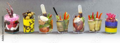 Mini desserts and meat canapes vegetable snacks in plastic cups canapes