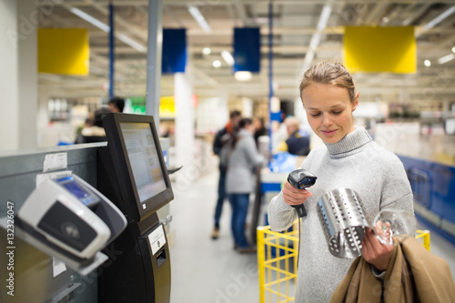 Pretty, young woman using self service checkout in a store photo