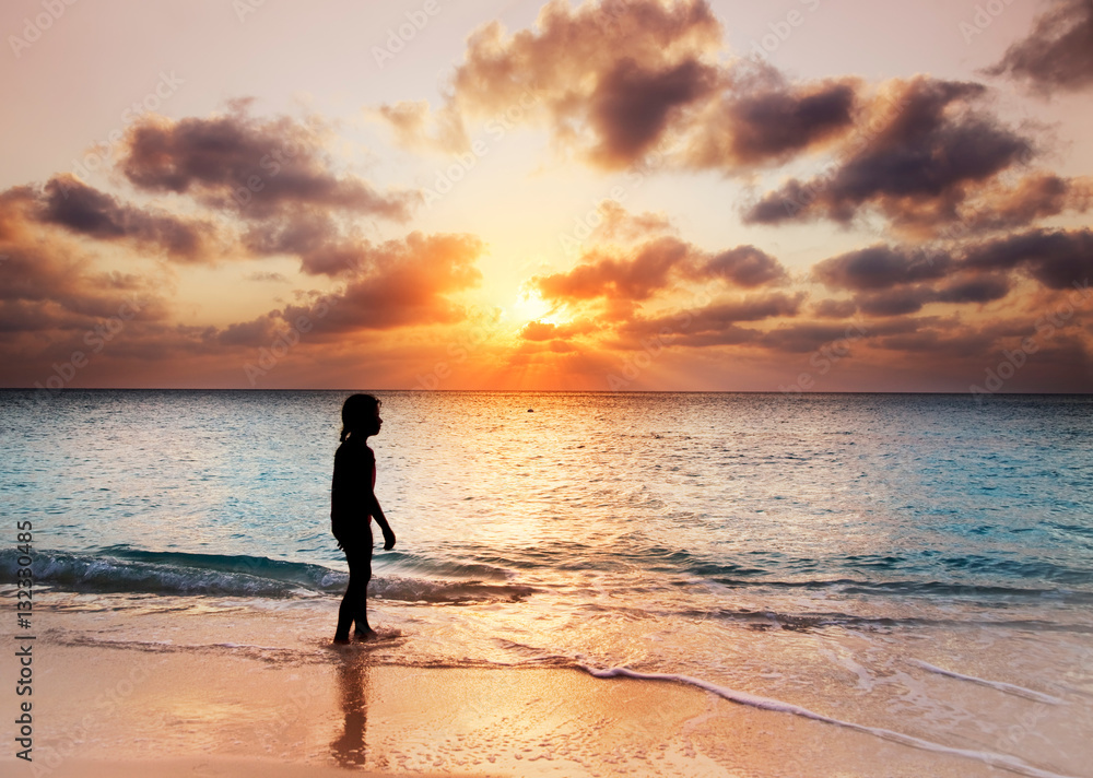 Child walking on Seven Mile Beach, Grand Cayman, at sunset