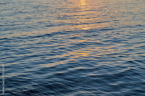 Texture of sea water at sunset, blue and orange colors of sun path