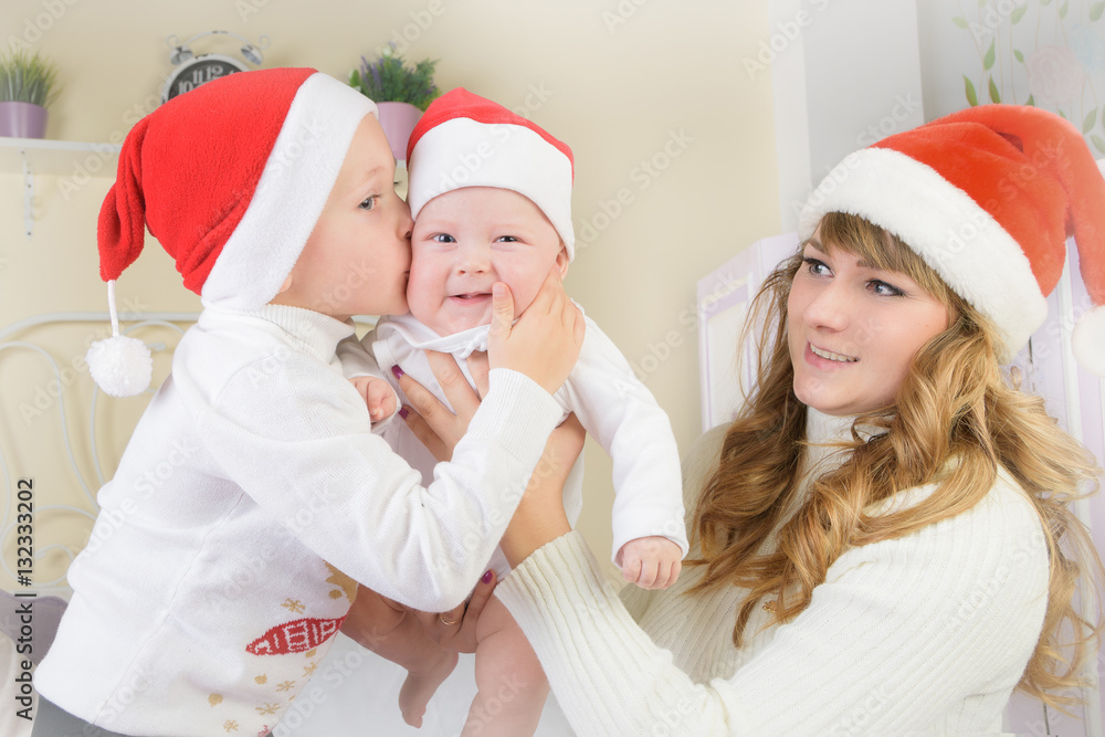 Fototapeta premium Mum holds on hands of the kid, and his son, kisses on the cheek