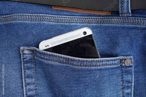 
Silver aluminum smartphone placed at the male stitched blue jean's back pocket