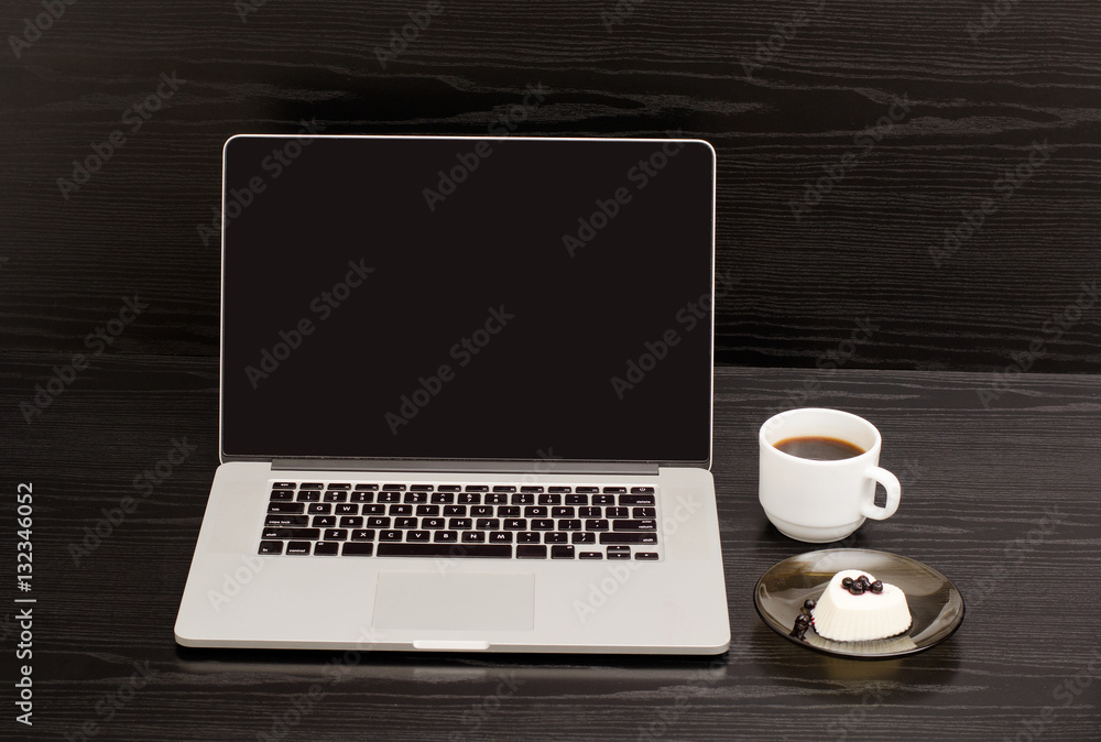 Open the laptop, mug of coffee and panna cotta on black wooden table, a lunch break Open the laptop, mug of coffee and panna cotta on black wooden table, a lunch break