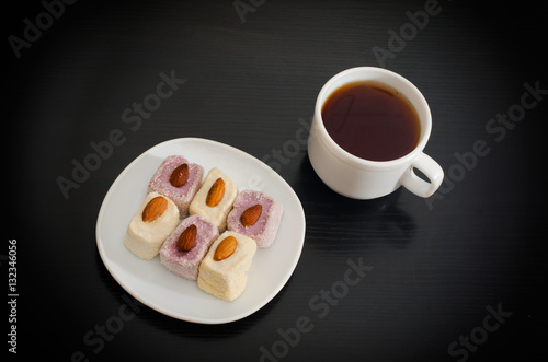 Cup of tea  saucer with Turkish Delight on a black table  top view