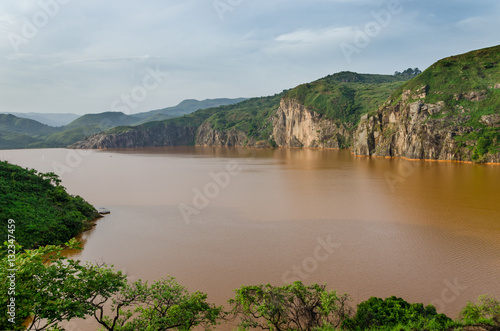 Landscape including calm brown water of Lake Nyos, famous for CO2 eruption with many deaths, Ring Road, Cameroon