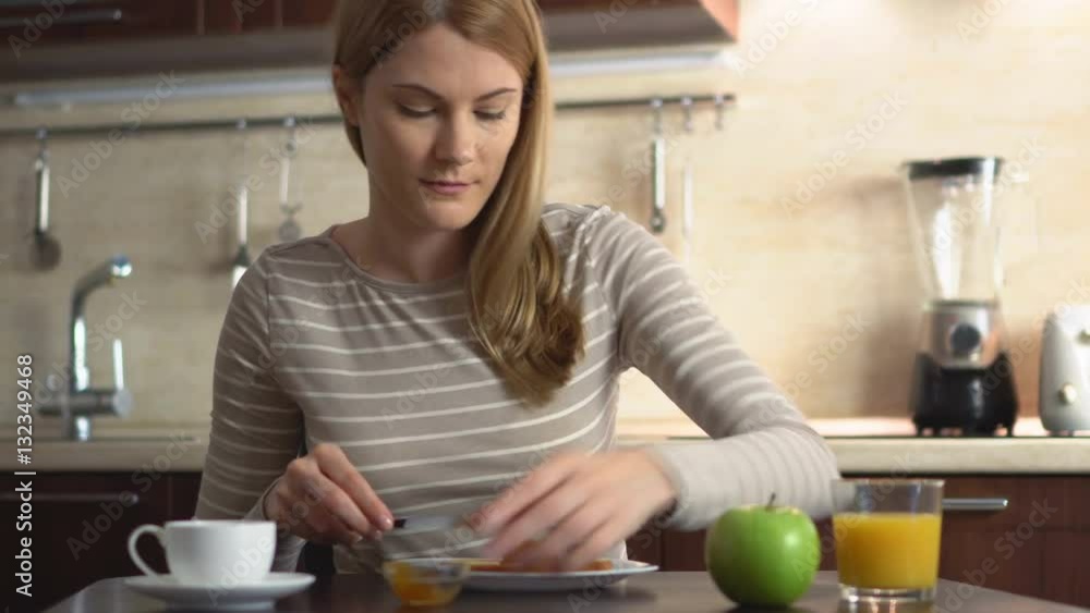 Beautiful young making bread and butter with jam. Breakfast with juice and coffee in the kitchen. Beautiful young making bread and butter with jam. Breakfast with juice and coffee in the kitchen.