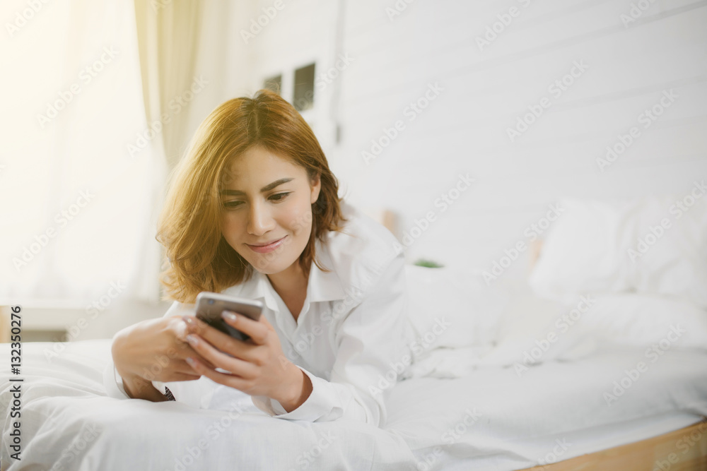 Relaxed Asia woman at home reading a text message in her bright bedroom Relaxed Asia woman at home reading a text message in her bright bedroom