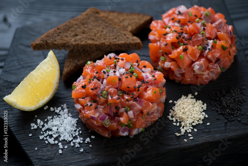 Close-up of salmon tartare served with sesame, bread and lemon