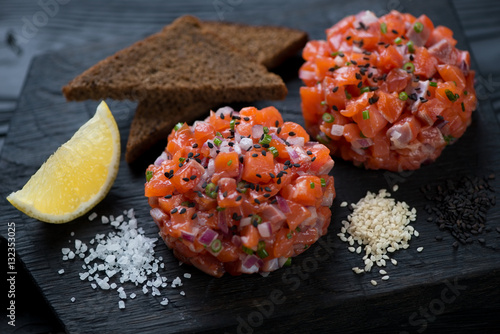 Close-up of salmon tartare served with sesame, bread and lemon photo