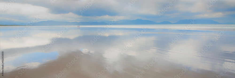 Inch Beach, Dingle Peninsula, Co. Kerry, Ireland.  Vast expanse of Inch beach with sky reflected along beach.  Two tiny figures in the distance emphasising the vastness of this iconic beach