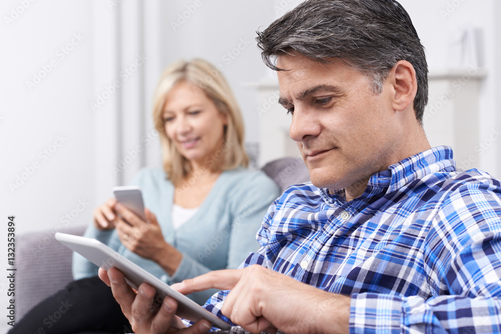 Mature Couple Using Digital Devices At Home