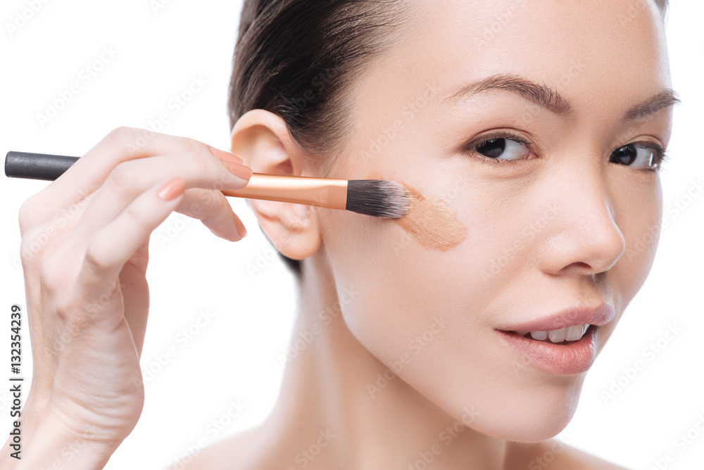 Happy positive woman applying foundation make up Happy positive woman applying foundation make up