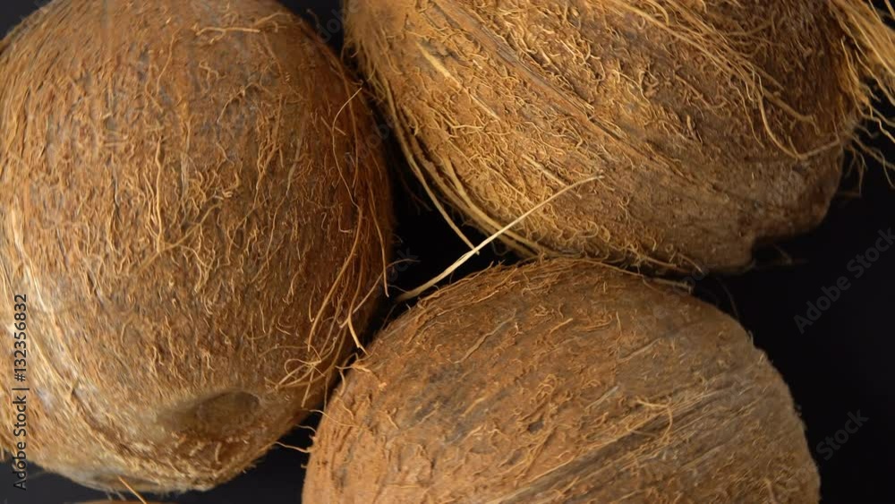 Three ripe tropical coconuts rotating on a black background. Tropical fruits and food concept. Loop, Three ripe tropical coconuts rotating on a black background. Tropical fruits and food concept. Loop,