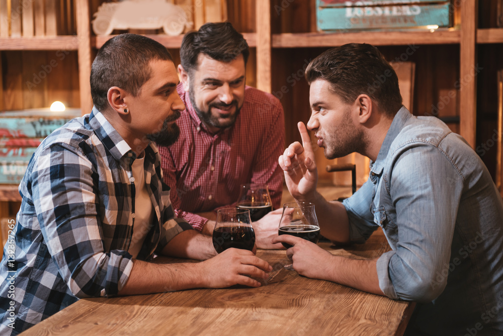 Pleasant nice man telling his friends a secret Pleasant nice man telling his friends a secret
