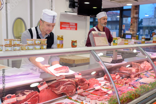 butcher preparing meat behind counter photo