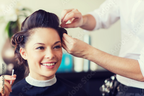 happy woman with stylist making hairdo at salon