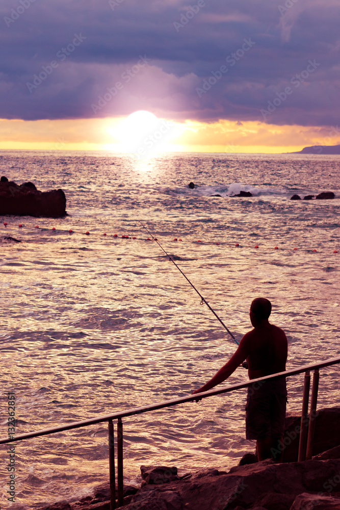 Silhouetted fisherman and seaside sunset in Tenerife