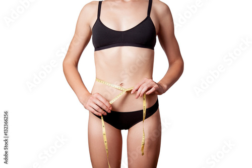 Slim fit happy young woman with measure tape measuring her waist with black underwear, isolated on white background. studio shot. 